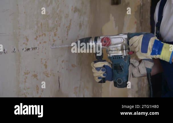 Builder working with a rotary hammer drill. Contractor drills holes in ...