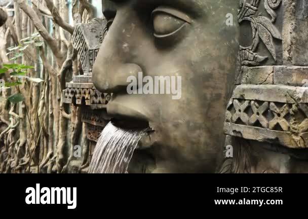 An ancient stone statue of the face of a deity in the jungle with a ...