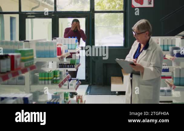 Sick male client entering drugstore with painful headache, asking ...