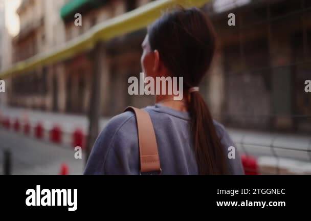 Young woman with bag on her shoulder walking on the street in the ...