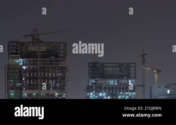 Tall buildings under construction and cranes in downtown night ...