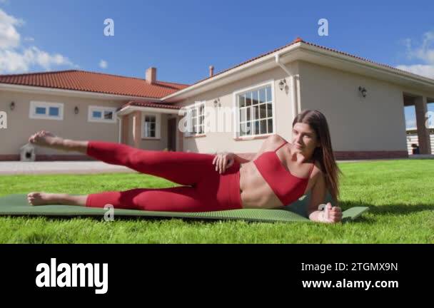 Young Caucasian Woman Doing Side Leg Lifts With Beautiful House Behind