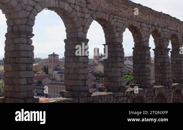 Stone arches of the aqueduct of Segovia with medieval buildings in the ...
