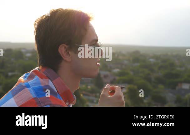 Profile of handsome man in sunglasses standing on the edge of rooftop ...