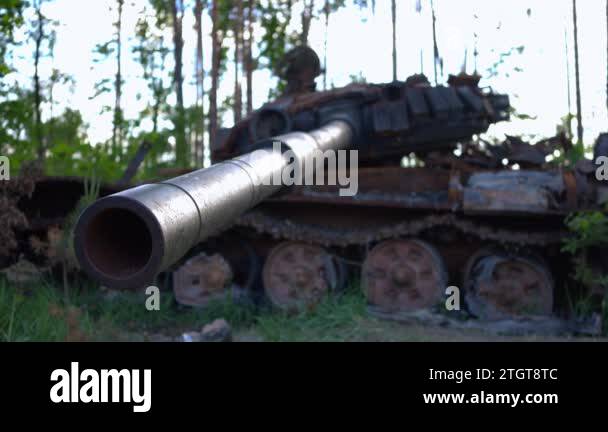 Close-up tank muzzle with blurred burnt down military vehicle at ...