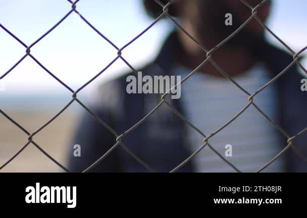 https://c8.alamy.com/comp/2th08jr/closeup-of-man-resting-hand-on-a-chain-link-fence-against-a-blurry-urban-background-male-stuck-behind-a-gate-locked-in-and-stuck-with-social-issues-depression-or-financial-problems-with-copyspace-2th08jr.jpg