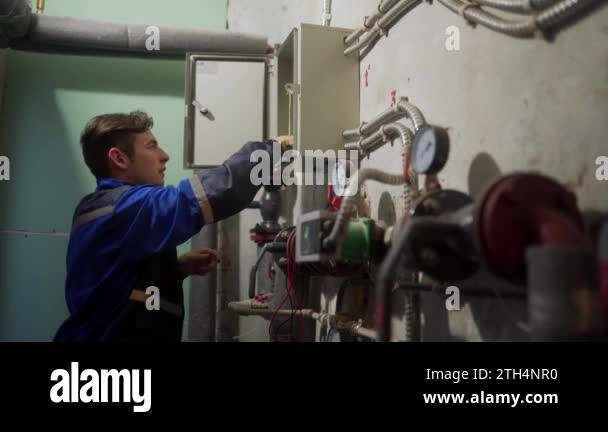 Electrician inspecting electrical fuse box. Master in uniform screwing ...