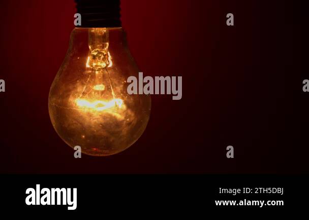 Light bulb goes out on a red background in the dark. Slow turning off ...