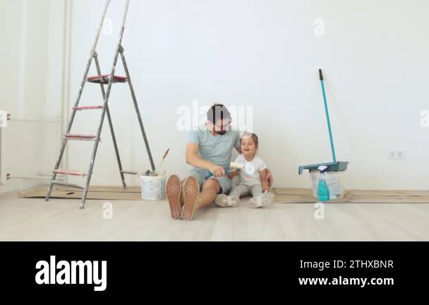 Young father and his little blonde cute girl daughter with wall paint ...