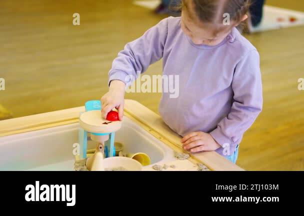 Little girl playing with kinetic sand and wooden toys. Sensory ...