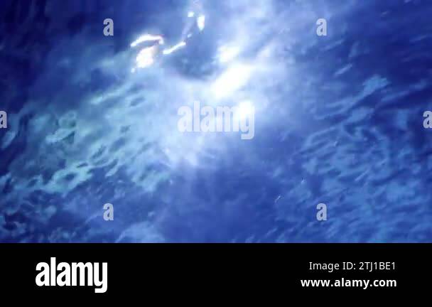 Sun light beams and rays shining through water surface in swimming pool ...