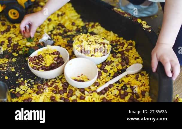 Child playing with sensory flakes in sandbox for playing. Sensory ...