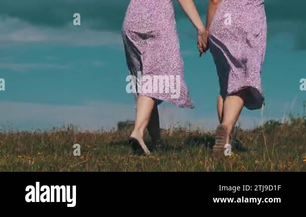 Back view of young twins sisters in summer dresses and straw hats ...