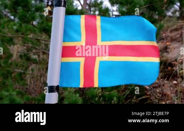The Aland flag flutters in the wind. The Aland Islands are an ...