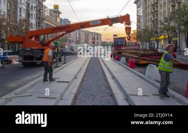 Orange construction telescopic mobile crane unloading tram rails from ...