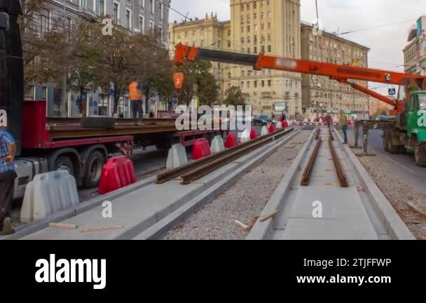 Orange construction telescopic mobile crane unloading tram rails from ...