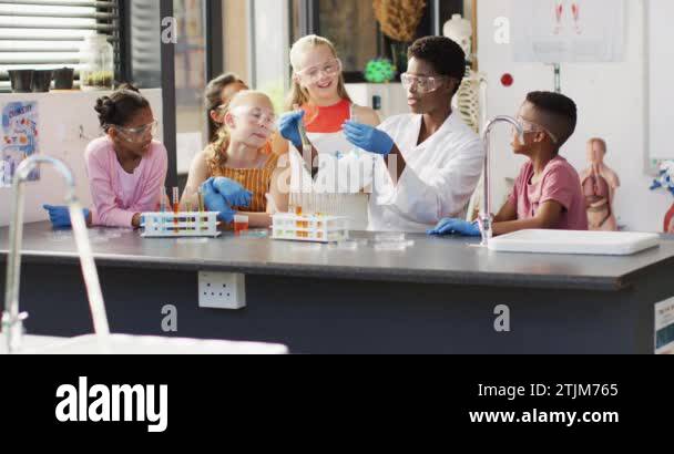 Diverse female teacher and happy schoolchildren having science class in ...