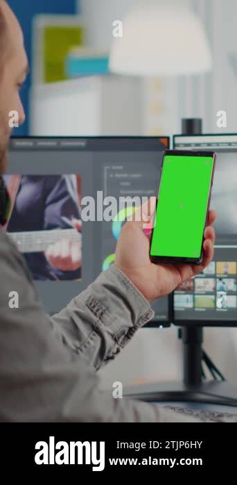 Video editor talking on video call holding smartphone with green screen ...