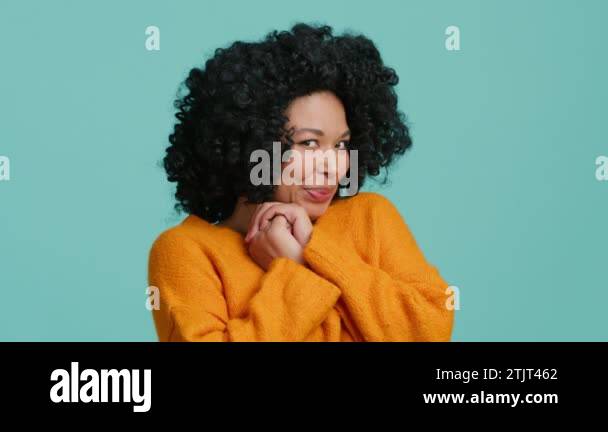 Melted positive dark skinned woman with afro hairstyle keeps hands on ...