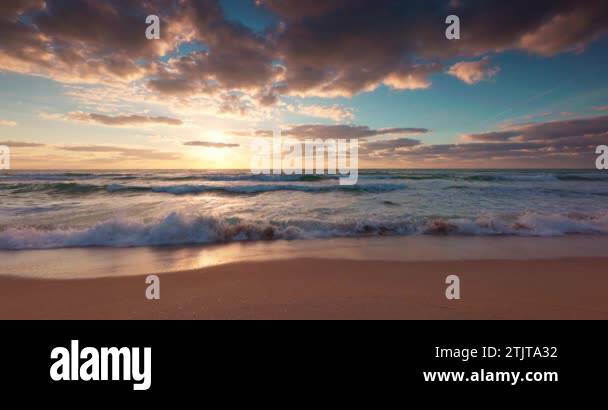Ocean beach sunrise with color sky clouds and sun rays over sea waves ...