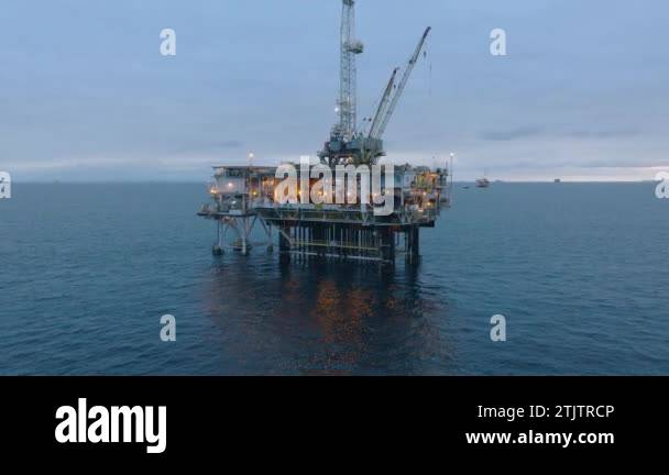 Evening view of illuminated oil drilling rig, fully equipped with ...