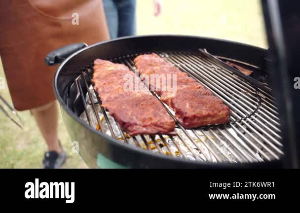 Marinated and seasoned pork ribs grilling on bbq grid in portable ...