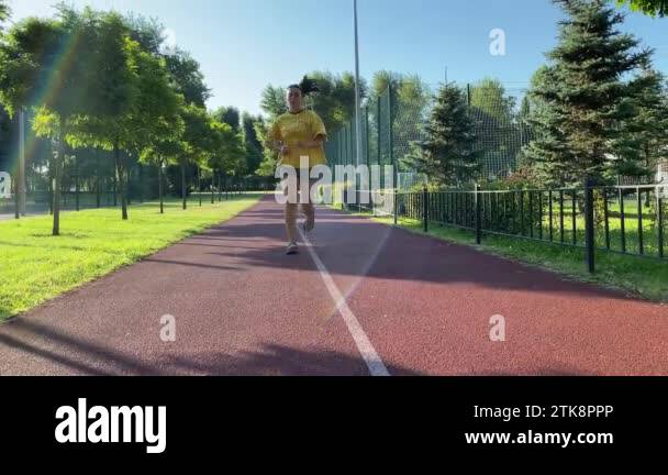 Multiracial young woman engages in a brisk jog on the running trail in ...