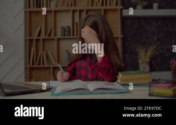 Cute irritated Latin teenage girl writing school assignment into ...