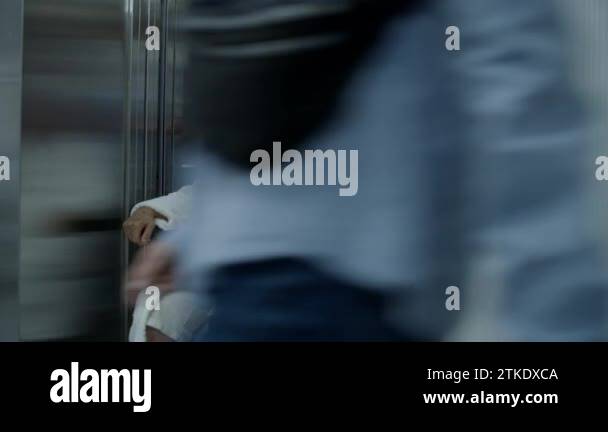 Doctor moves elderly woman in transport wheelchair from elevator. Medic ...