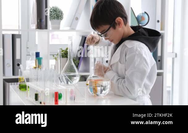 Schoolboy at chemistry lesson making experiment with orange chemical ...
