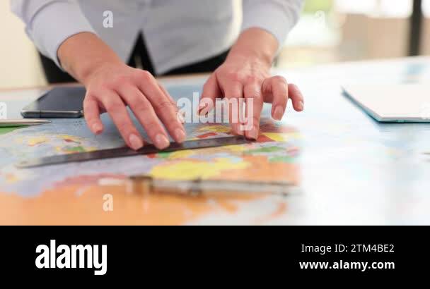Woman with ruler takes measurements on world map. Specialist ...