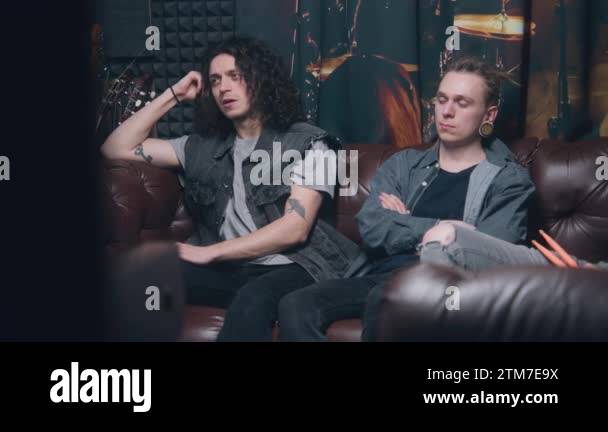 Musical rock band sits on couch Stylish male musicians artists