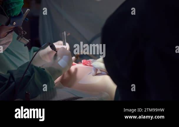 Surgery on breast augmentation in operating room indoors. Nurse helping ...