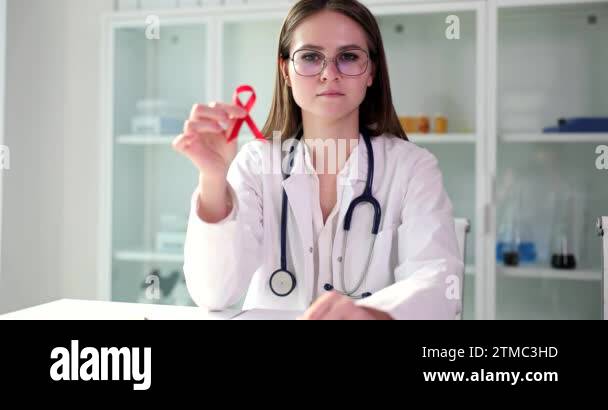 Doctor woman shows red ribbon symbol of World AIDS Day. HIV AIDS causes ...