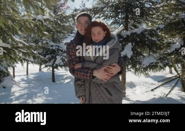 A married couple hugging while standing in the middle of a snowy park ...