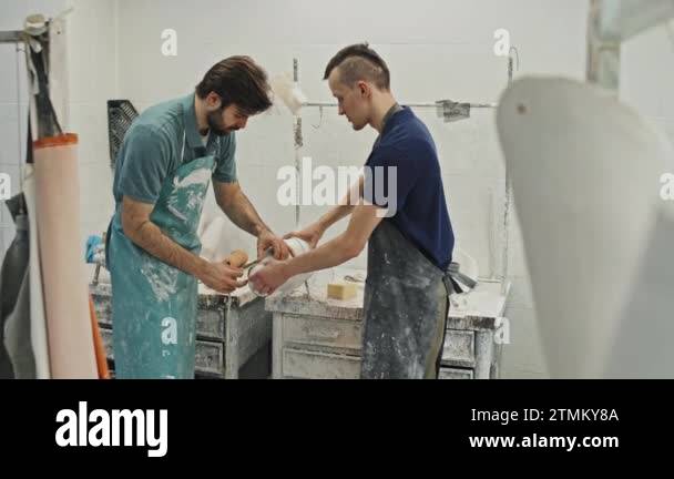 Two young adult Caucasian craftsmen taking measures of plaster cast for ...
