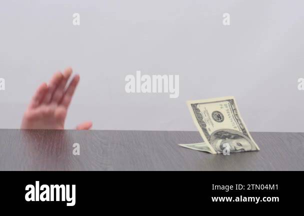 Child's hand showing from under the table and steals banknote. Hand of ...