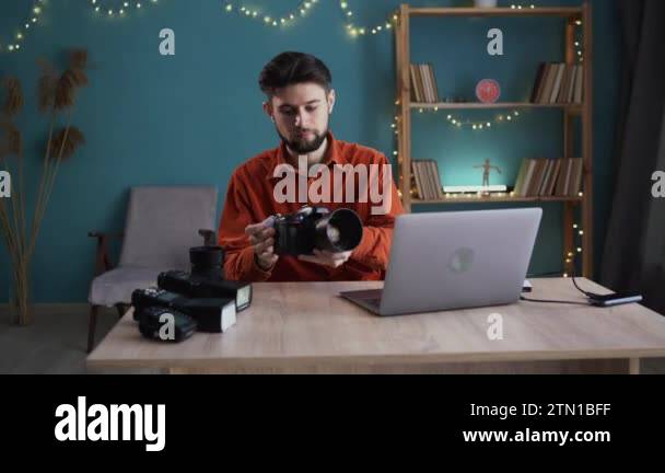 Photographer working on a laptop at the workplace sends captured images ...