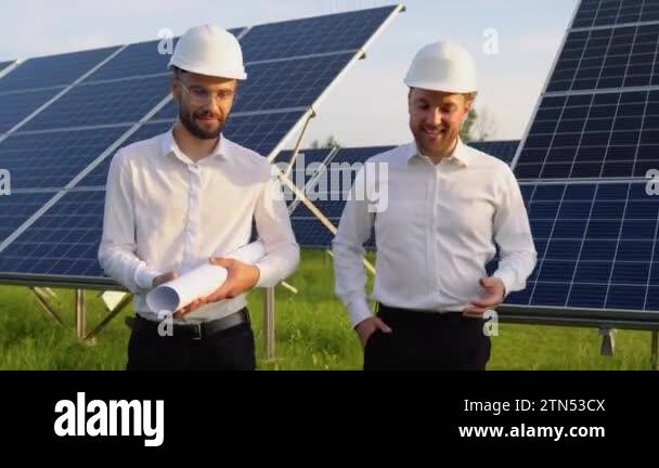 Two engineers walking and examining photovoltaic solar panels. Concept ...