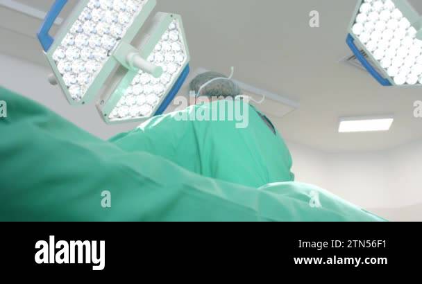 Caucasian male surgeon wearing surgical gown, using defibrillator on ...