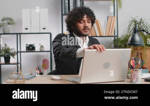 Indian businessman working on laptop computer, meditating, doing yoga ...