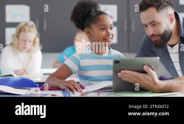 Diverse male teacher and happy schoolchildren using tablet in school ...