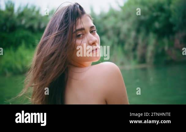 Portrait gorgeous naked woman looking camera at lake. Beautiful brunette model resting tropical