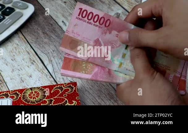 Counting 100,000 rupiah by hand on black background. Indonesian ...