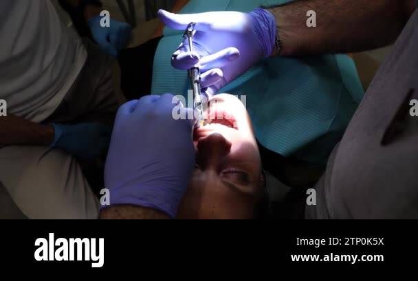 Dentist in medical gloves injects anesthesia into young woman tooth in ...
