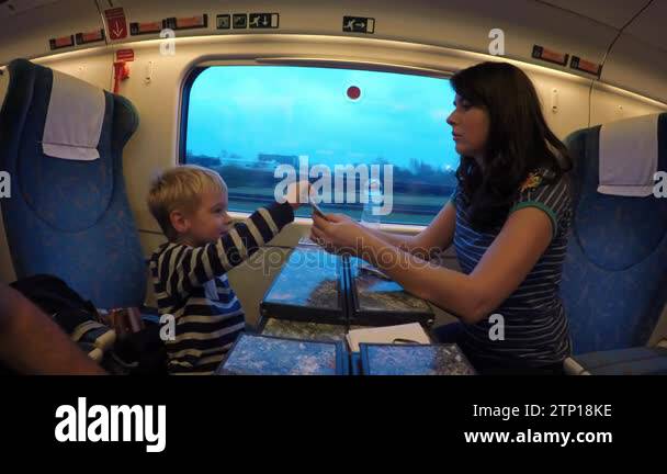 A young mother and her son travel by train.Woman and child playing card ...