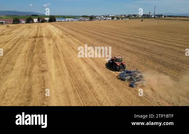 Tractor Raking Fields Red tractor ride across field with blue mountains in the background ...