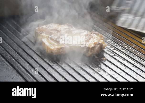 A cook turns up a steak of meat on a grill in slow motion Stock Video ...
