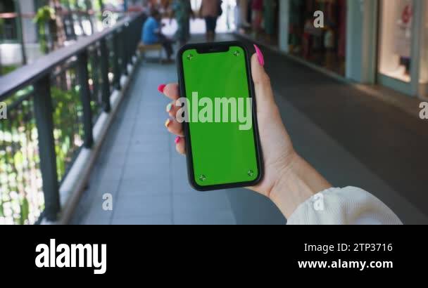 Close up woman hand holding mobile phone with vertical green screen ...
