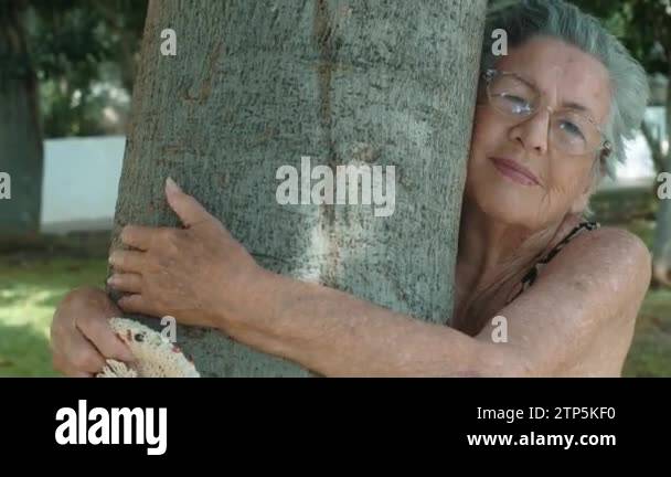 old 90s woman hugging a tree with love for nature . Happy and serene ...